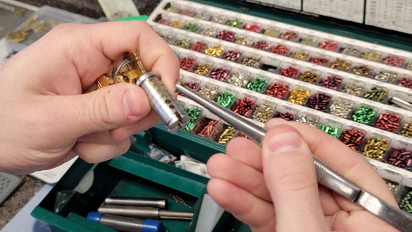 Image of a locksmith rekeying a lock by replacing the pins in the lock cylinder to match the cut pattern in a new key.